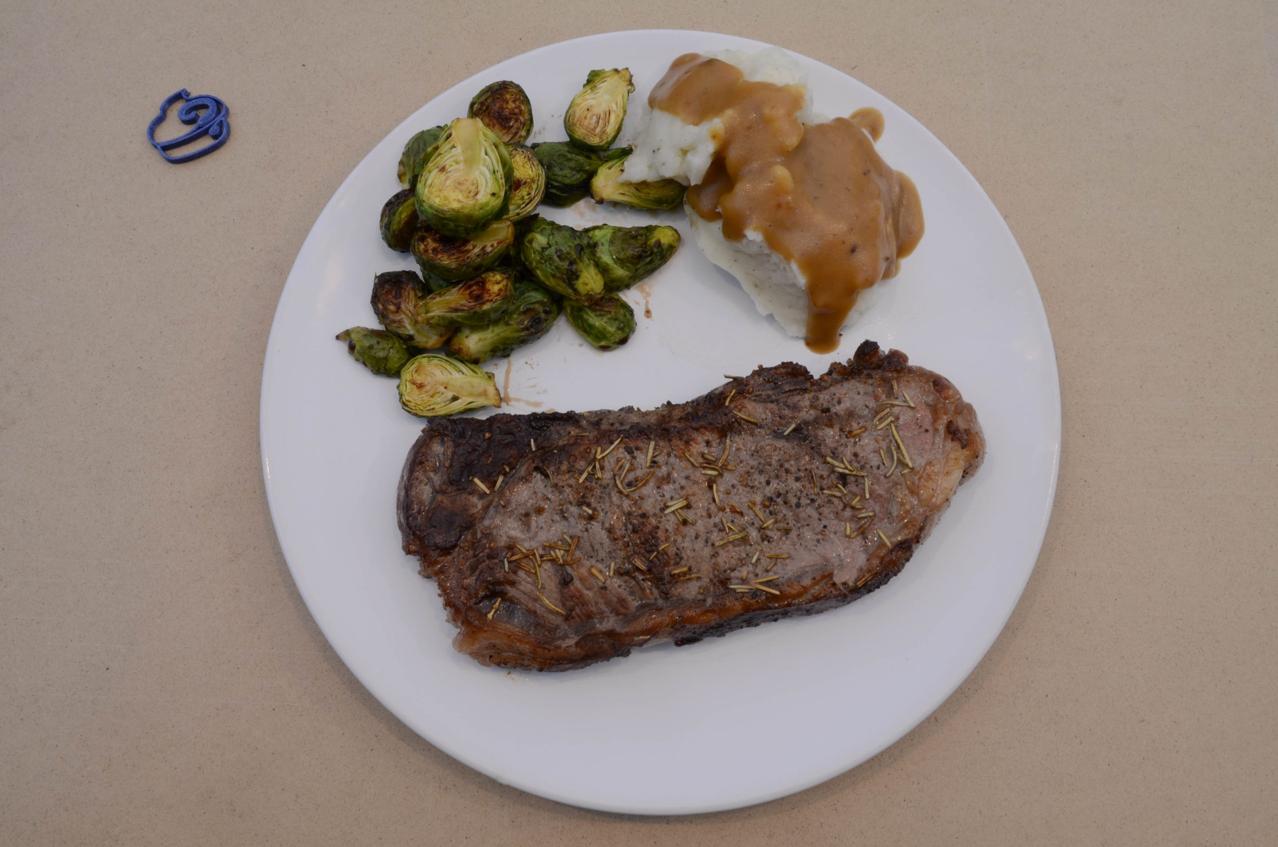 A dish with brussels sprouts as a side to steak and mashed potatoes
