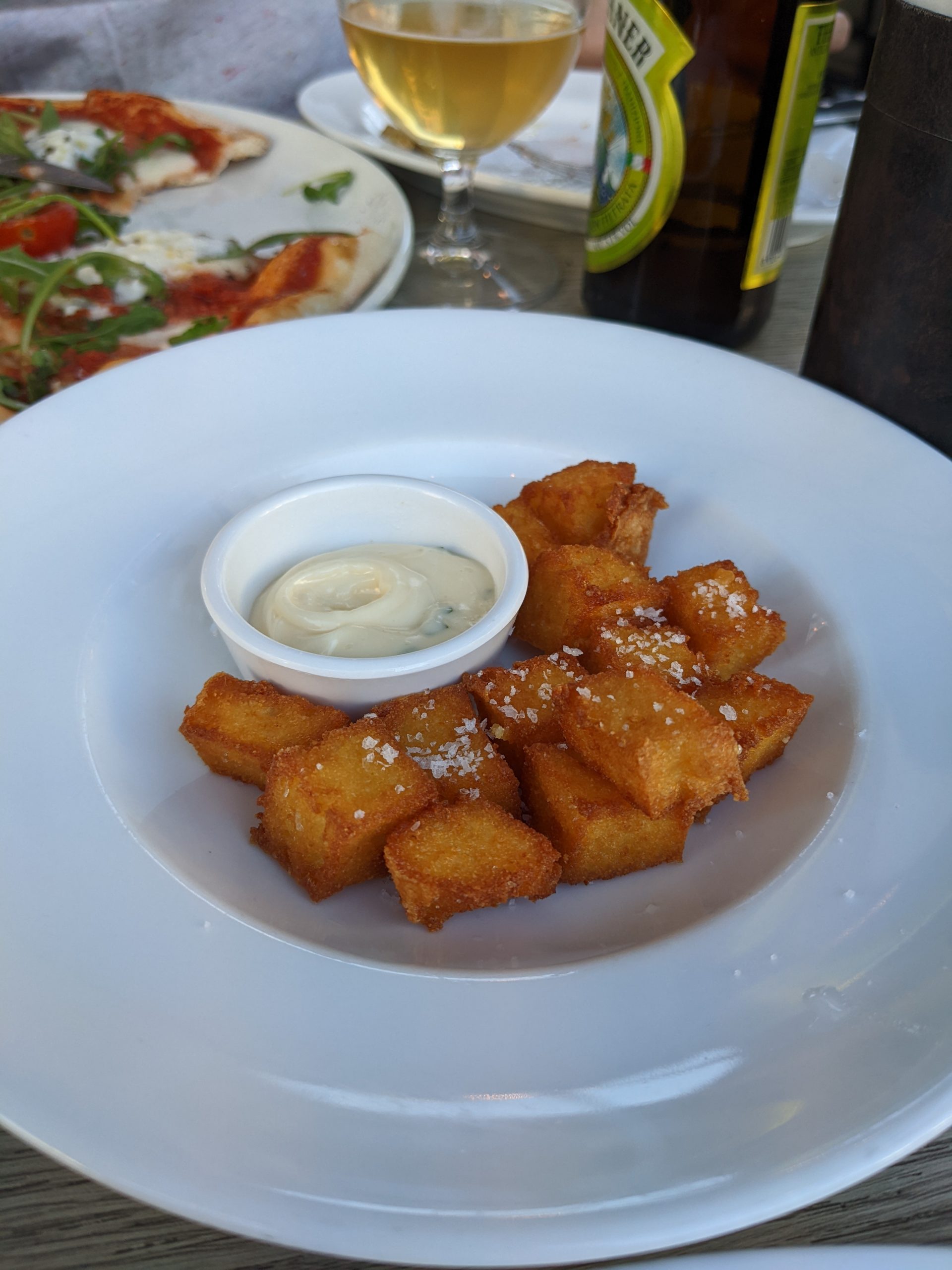 A plate of fried polenta with a dish of dipping sauce