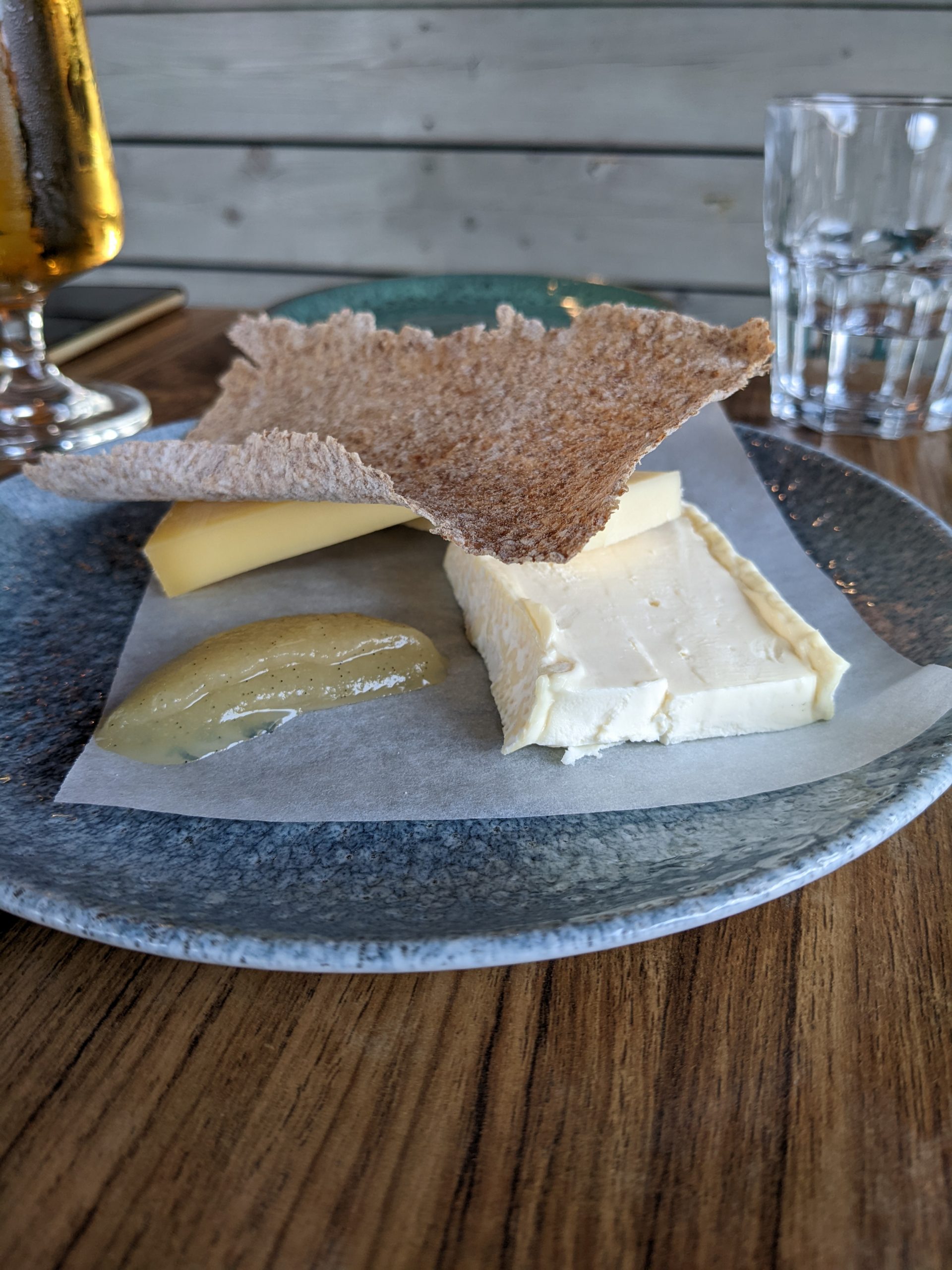 An assortment of cheese sitting on a blue plate with a thin cracker on top