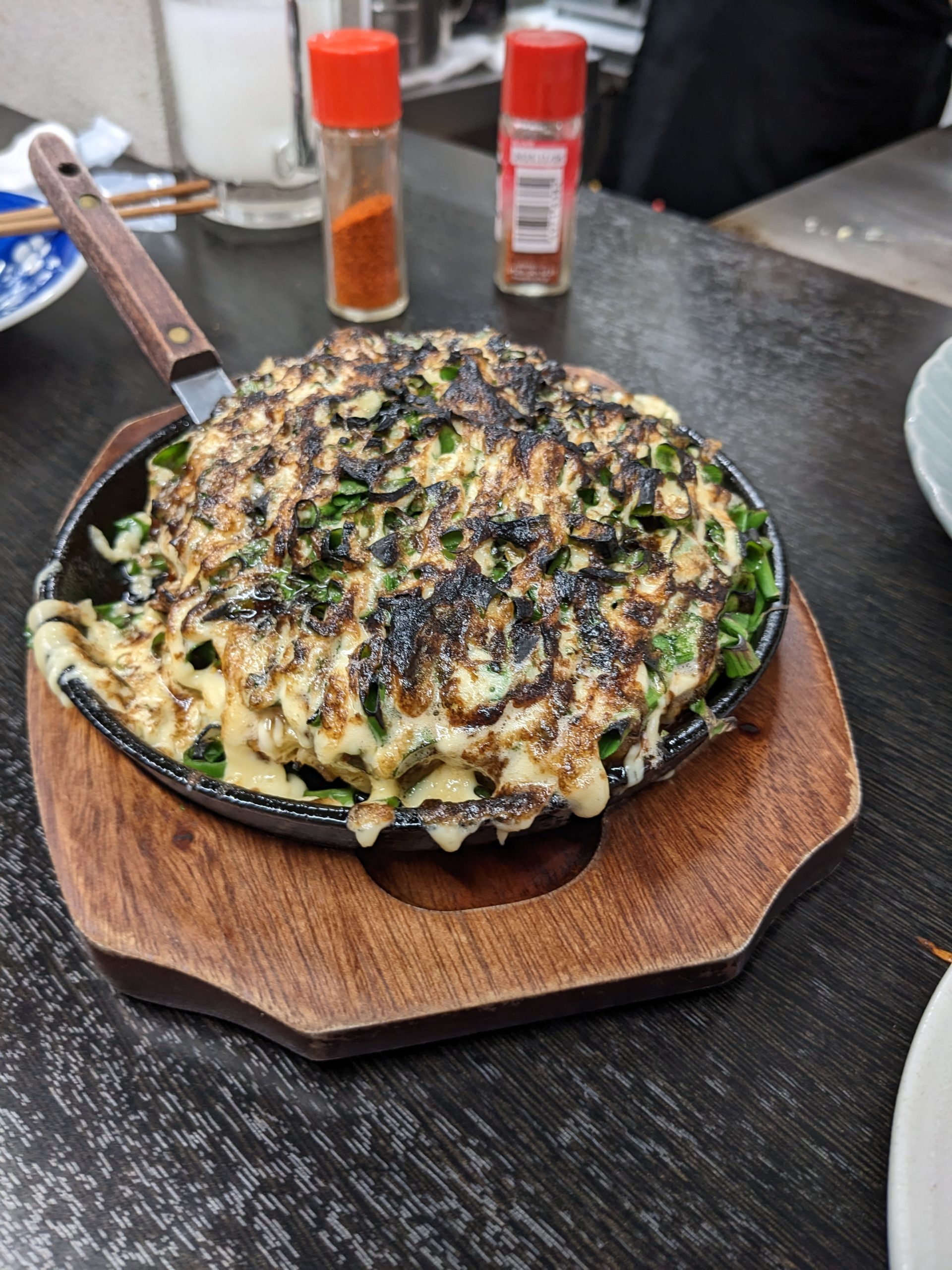 A pan full of okonomiyaki covered in mayonnaise